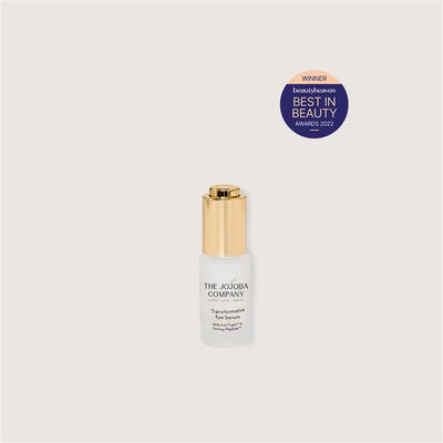 Skincare serum bottle with gold cap on a light gray background, featuring an award badge.