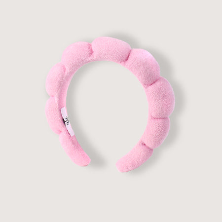 Pink fuzzy headband on a light gray background